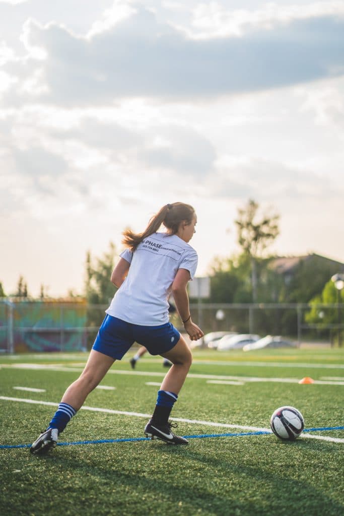 Frau spielt Fußball im Freien auf einem Rasenplatz