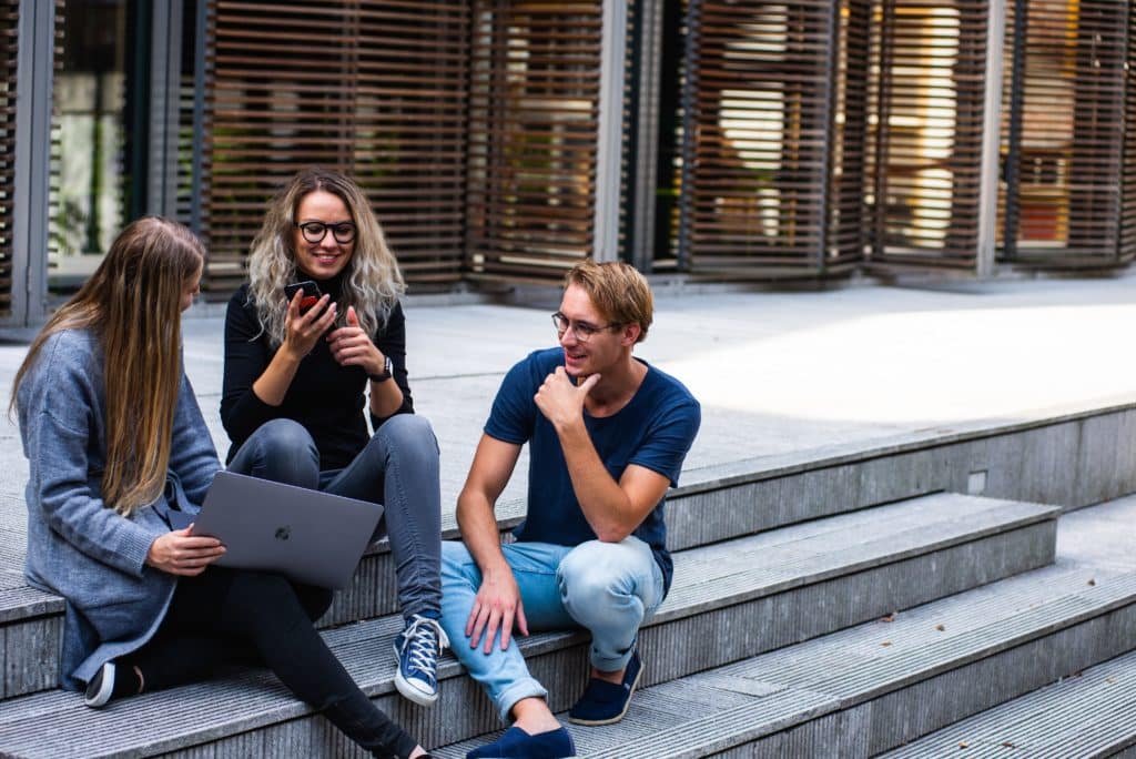 Junge Leute lachen und sprechen auf Treppe draußen